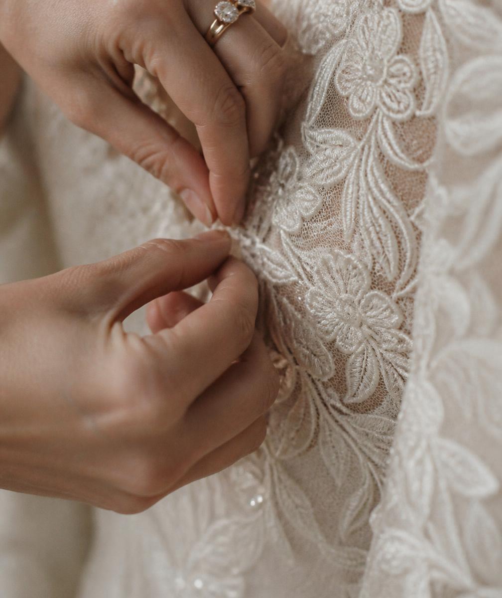 Manos ajustando el bordado de un vestido de novia