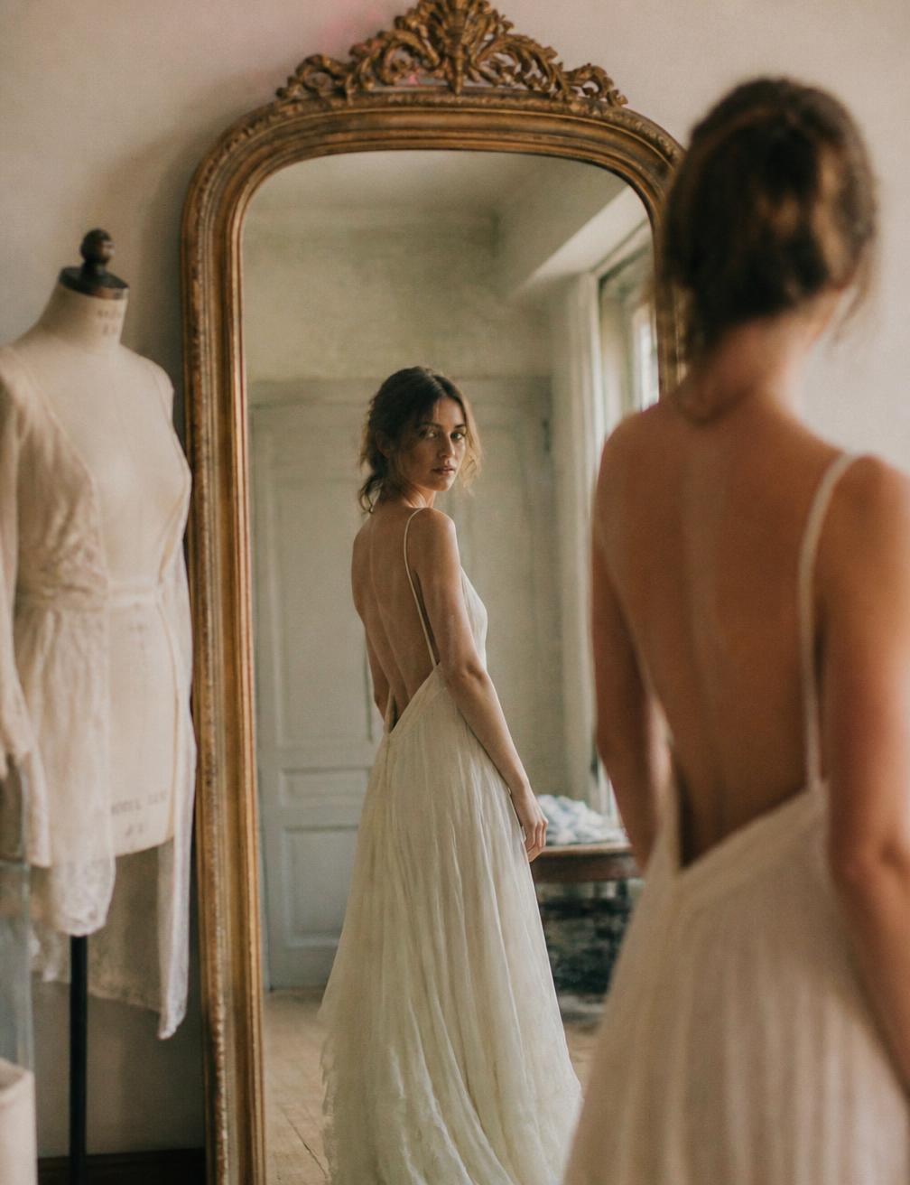 Mujer probándose un vestido frente a un espejo antiguo en el atelier